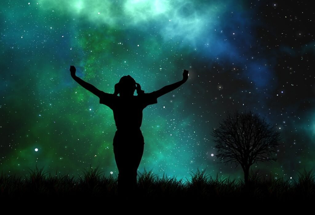 A little girl with her arms reaching out into the night sky.