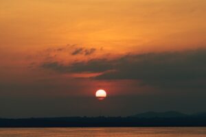 a large body of water with a sunset in the background