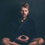 man in black hoodie sitting on black background