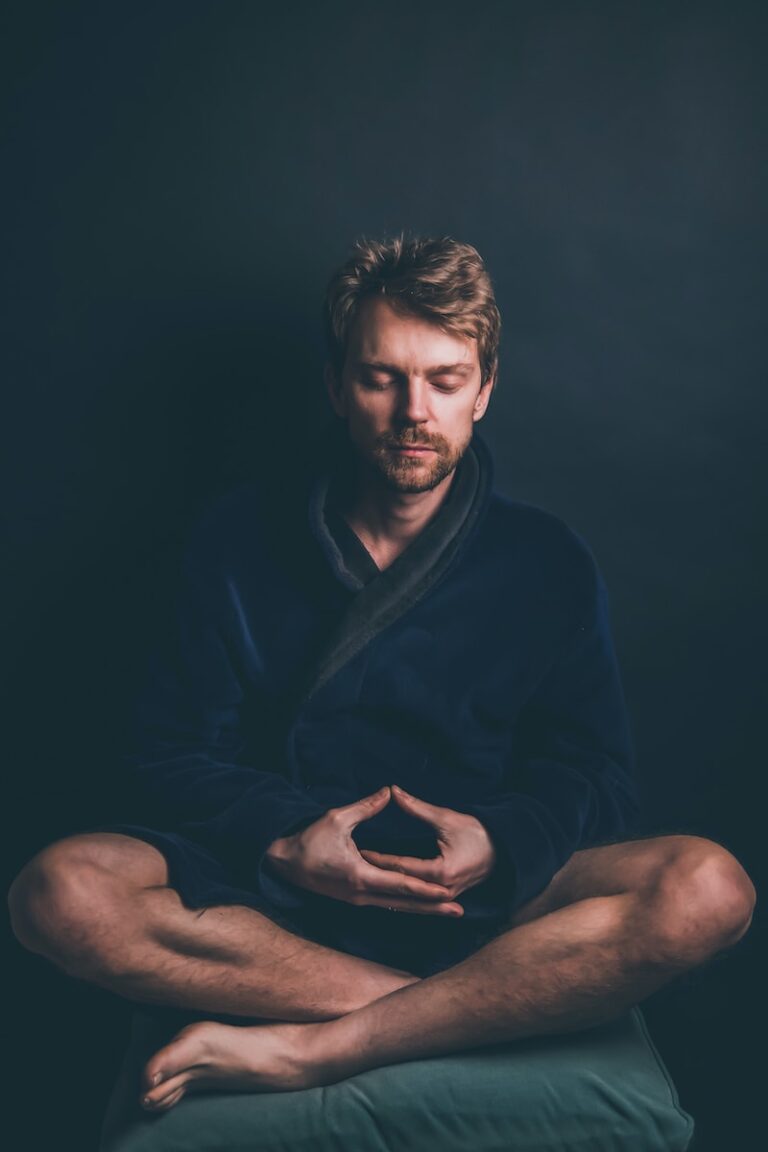 man in black hoodie sitting on black background