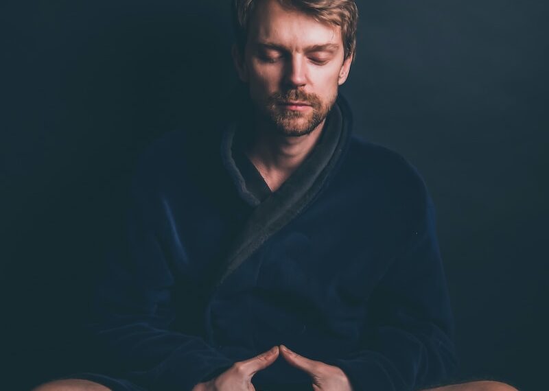 man in black hoodie sitting on black background