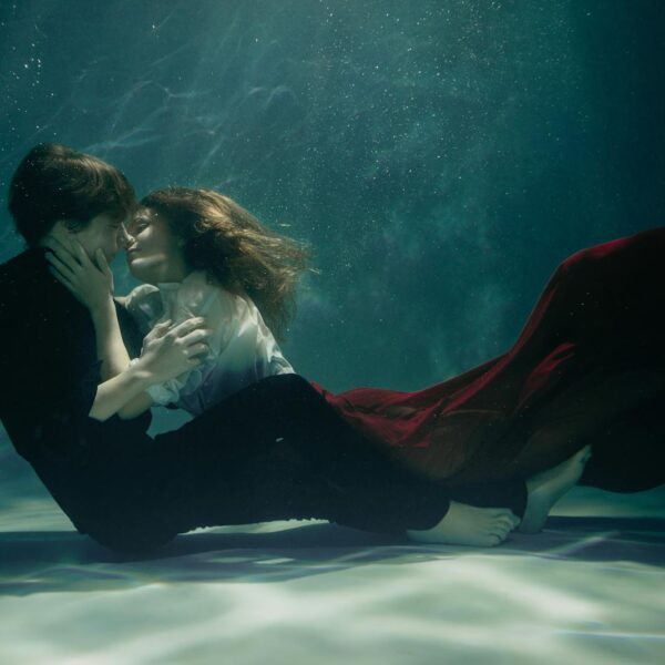 A couple embraces passionately underwater, creating a dreamy and romantic scene.