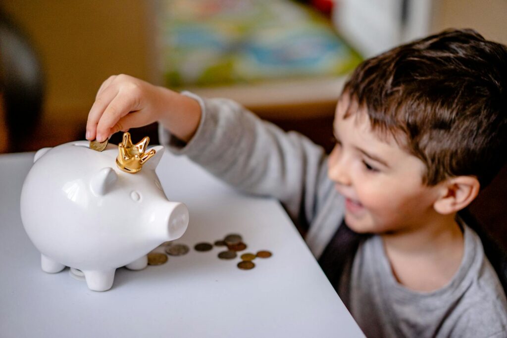 The young boy smiles while saving money in a crowned piggy bank to unlock prosperity