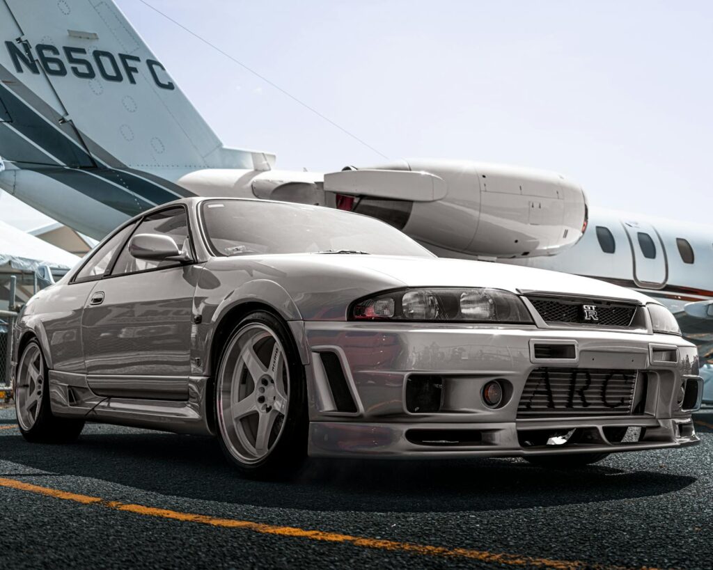 A silver sports car parked on the tarmac with a private jet in the background, all from visualization exercises