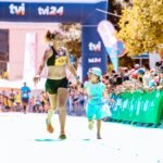 A joyful mother and daughter cross the marathon finish line hand in hand, exuding happiness and energy.