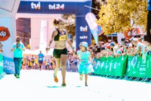 A joyful mother and daughter cross the marathon finish line hand in hand, exuding happiness and energy.