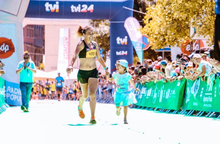 A joyful mother and daughter cross the marathon finish line hand in hand, exuding happiness and energy.