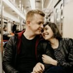 The young couple is sharing a tender moment together on a train journey.