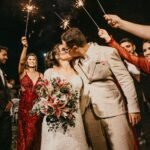 A joyful couple kisses because they used strategies for success to get married while standing under sparklers, surrounded by guests in a wedding celebration.