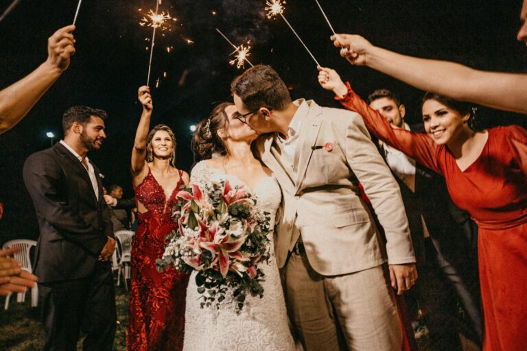 A joyful couple kisses because they used strategies for success to get married while standing under sparklers, surrounded by guests in a wedding celebration.