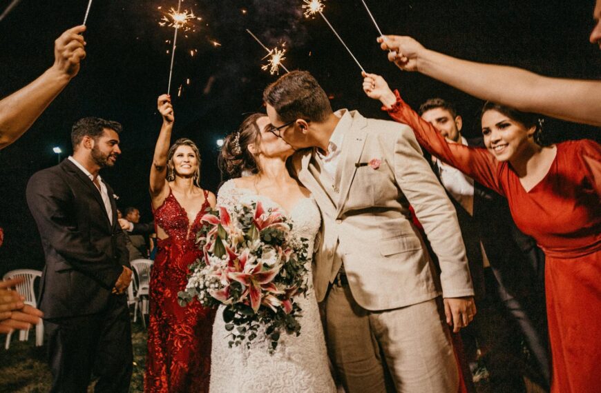 A joyful couple kisses because they used strategies for success to get married while standing under sparklers, surrounded by guests in a wedding celebration.