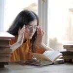 A young woman searching for the law of attraction secrets while reading and studying surrounded by books.