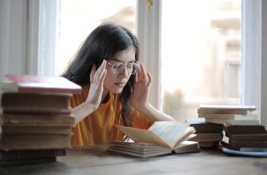 A young woman searching for the law of attraction secrets while reading and studying surrounded by books.