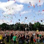 A lively crowd enjoying a colorful juggling event outdoors, celebrating and manifesting success