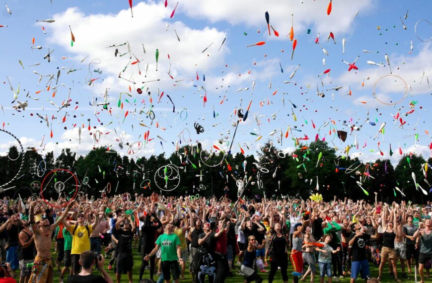 A lively crowd enjoying a colorful juggling event outdoors, celebrating and manifesting success