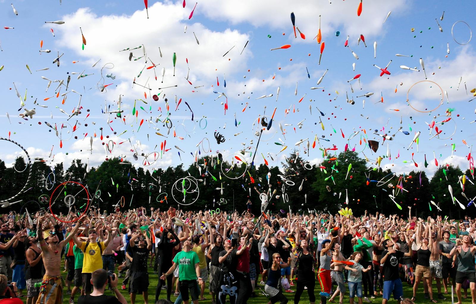 A lively crowd enjoying a colorful juggling event outdoors, celebrating and manifesting success