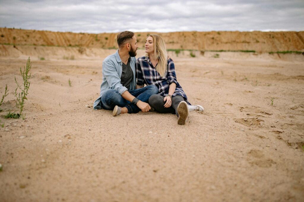 A couple sitting closely in a serene desert, discussing love and relationships.