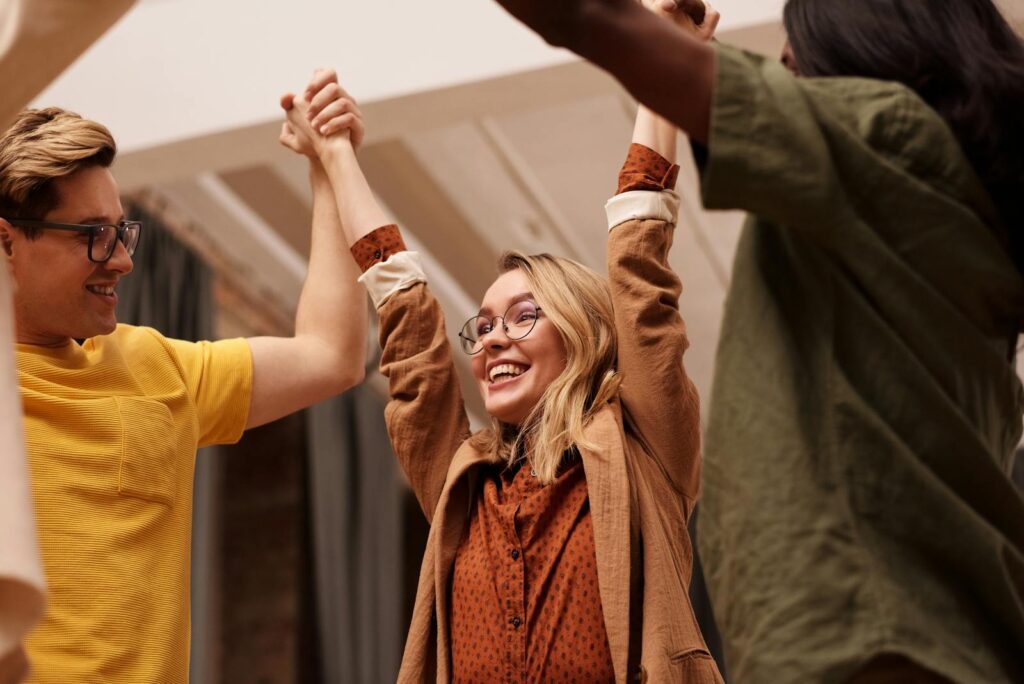 Joyful friends celebrating together with hands uplifted, symbolizing unity and happiness.