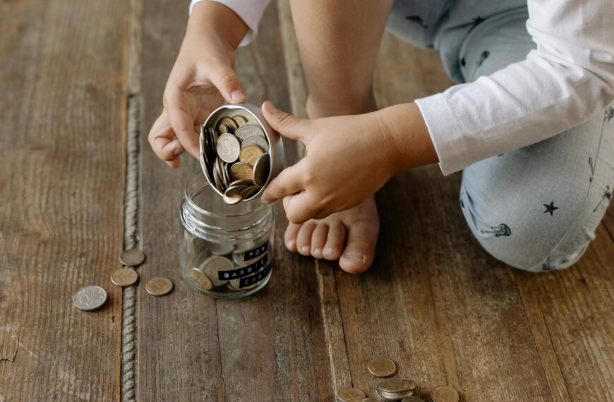 A child adds coins into a glass jar labeled for wealth and prosperity