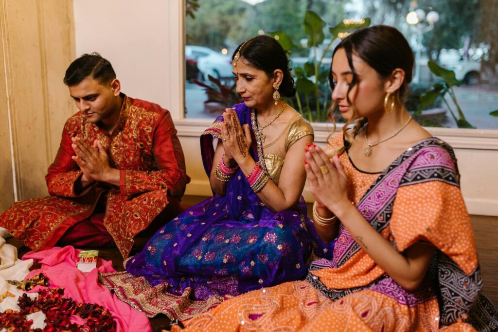 A family sitting indoors celebrating Diwali in colorful traditional clothing, hands in prayer leveraging the law of attraction