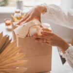 A woman opening a gift bag on a wooden table proves she can attract abundance